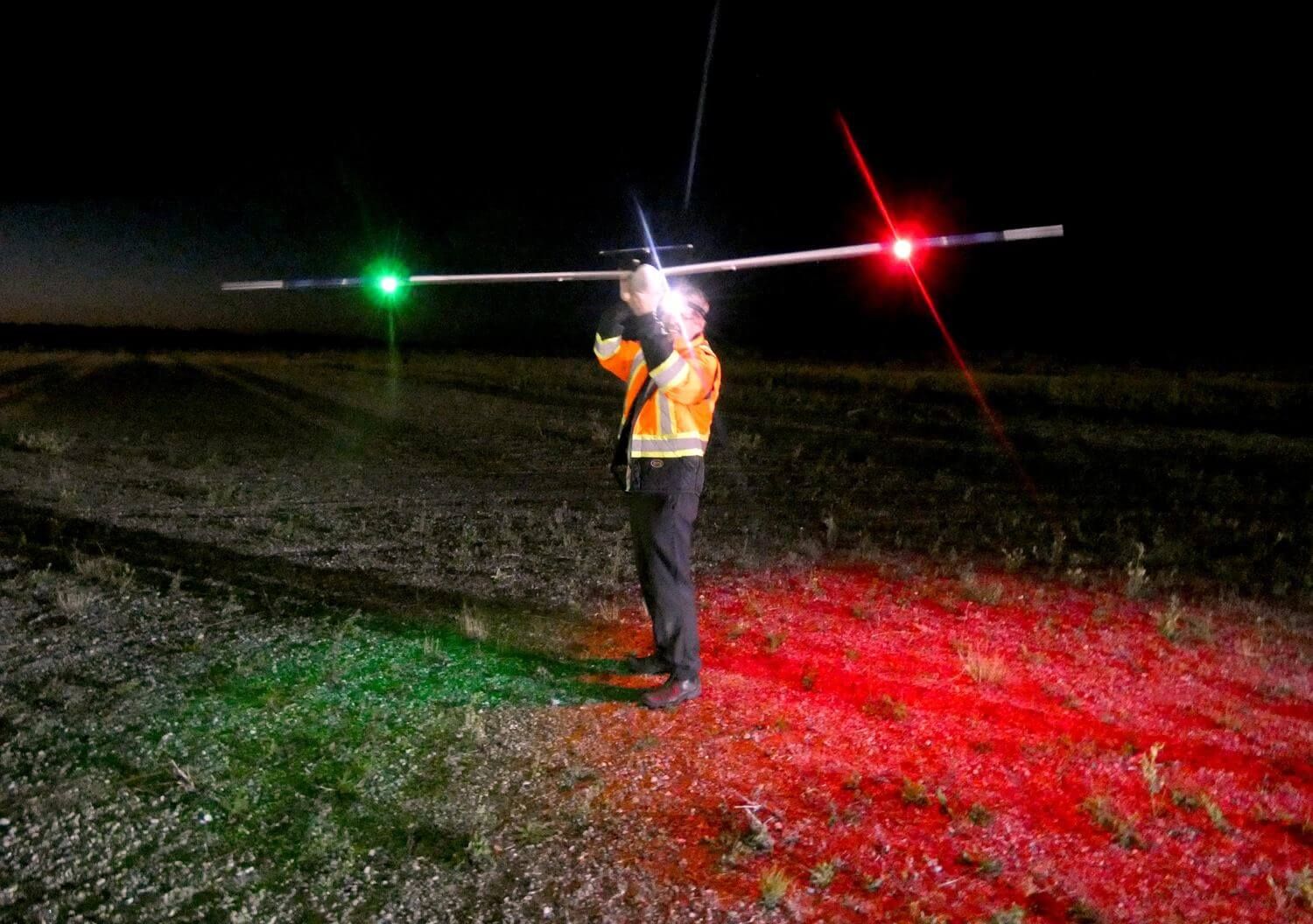 A ground crew member holds HiDRON at night, its navigation lights on